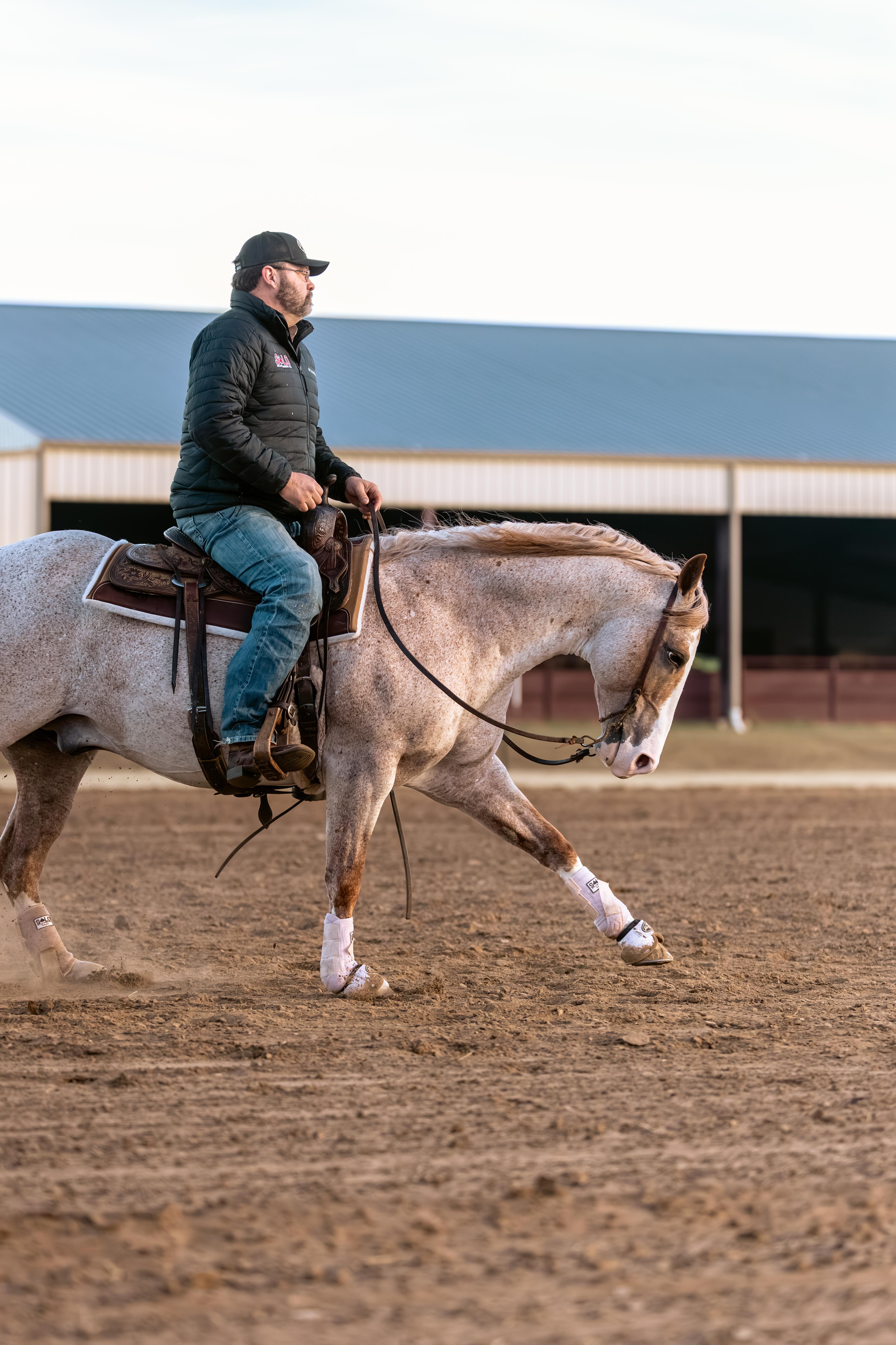 A rider loping a roan mare under saddle