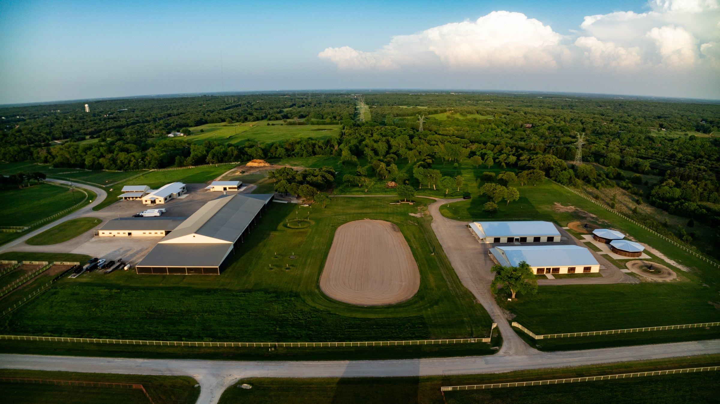 Aerial of the Solo Select barns, covered arena, and exercise track at golden hour