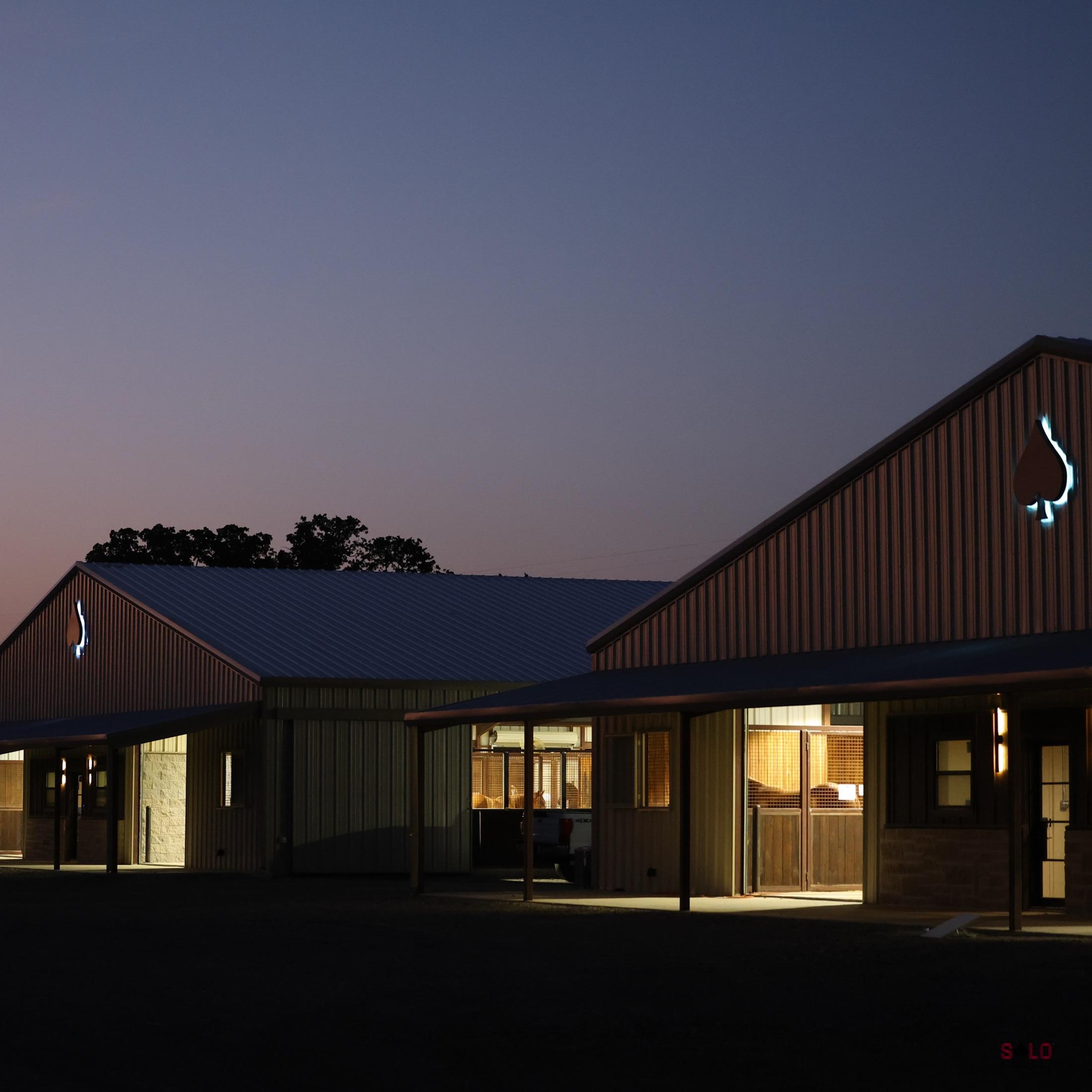 The Solo Select barns lit up at twilight, spade emblems glowing on the gables