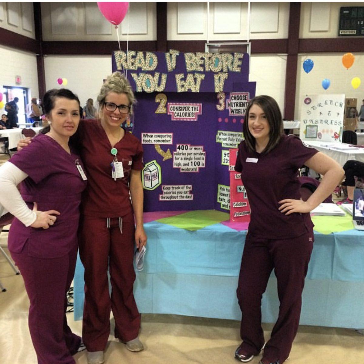 Melanie in maroon scrubs with nursing school classmates at a health fair