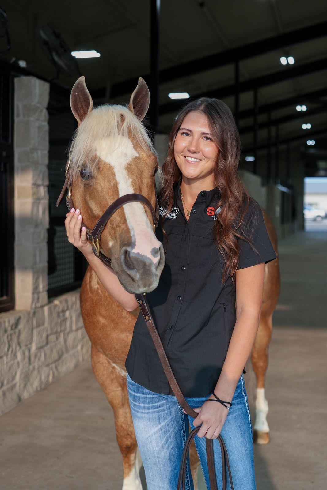 Dr. Shelby Horton, DVM, standing with a horse in the barn aisle at Solo Select